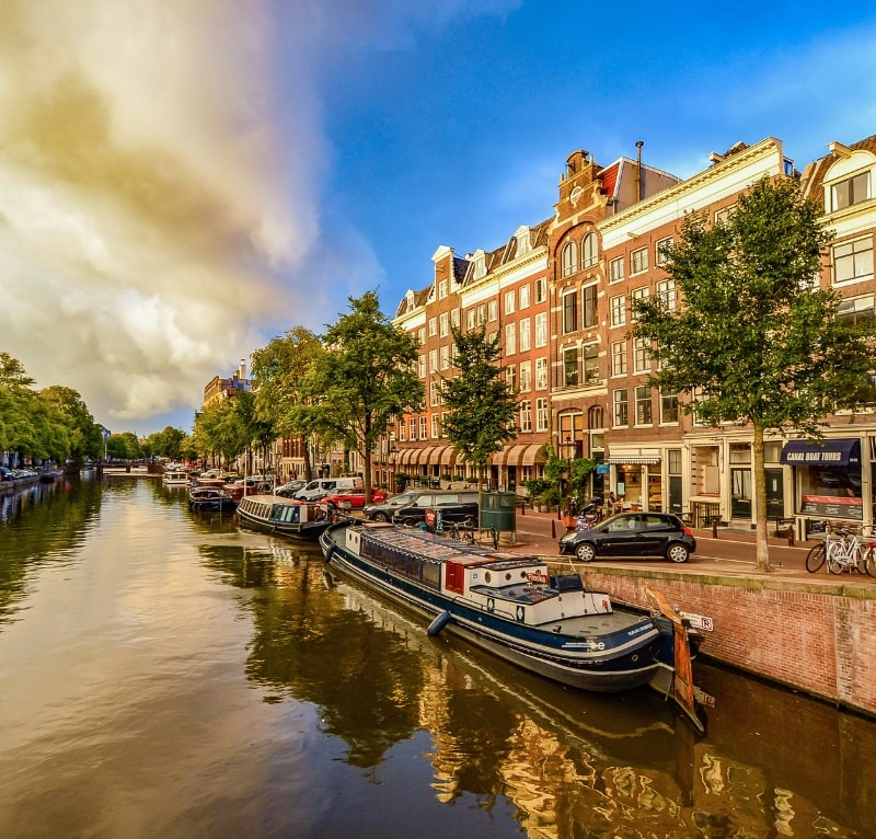 Fiume della città di Amsterdam con diverse barche parcheggiate