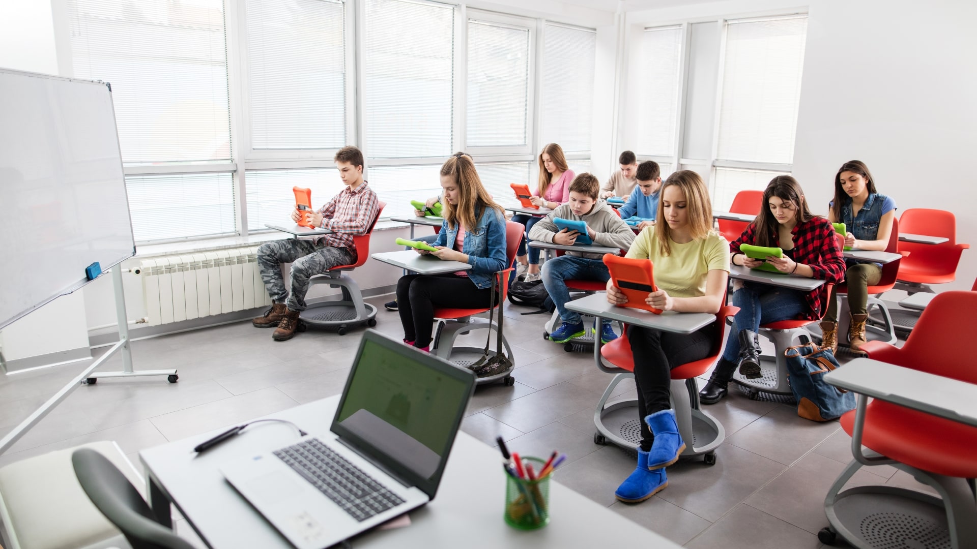 Aula moderna per corsi di lingua inglese a Genova, con studenti che utilizzano tablet in un ambiente luminoso e tecnologico.